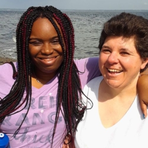 two women smiling together by the ocean